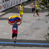 Atleta cruzando la línea de meta con la bandera de Venezuela