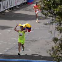 Atleta cruzando la línea de meta con la bandera de Colombia
