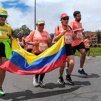 Grupo de amigos veteranos corriendo con la bandera de colombia