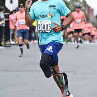 Corredor sin piernas usando prótesis avanzando en la media maratón de Bogotá