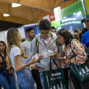 Asistentes interactuando con el personal del stand comercial