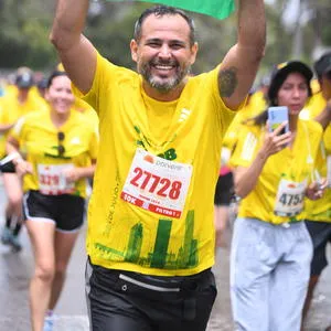 Atleta corriendo con la bandera de Colombia la media maraton de bogota