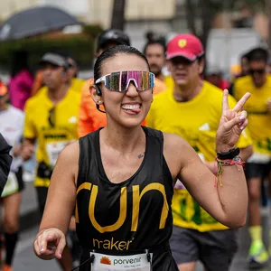 Mujer sonriendo con la mano arriba mientras corre por las calles de bogota