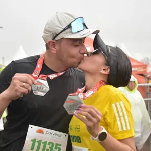 Pareja besándose mientras tienen la medalla