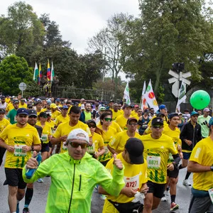 Hombre con impermeable verde corriendo por las calles de Bogotá