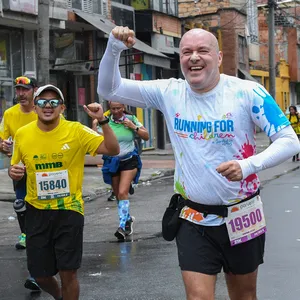 Hombre con mano arriba y puño cerrado corre por las calles de Bogotá