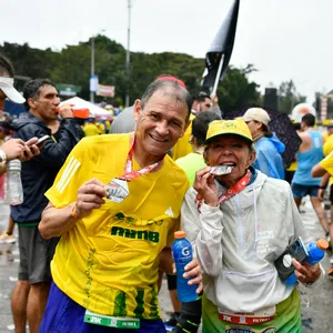 Pareja de adultos celebran mordiendo la medalla después de recorrido de 21 K