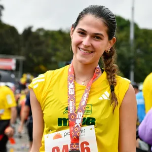 Mujer sonriendo con trenza posa con medalla