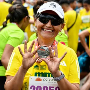 Mujer enseña medalla en zona de concentración