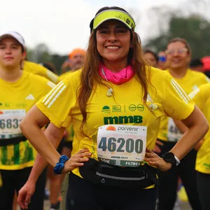 Atleta joven con audífonos y visera viendo a cámara y sonriendo