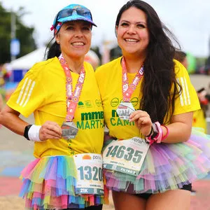 Dos mujeres con tutu enseñan medalla de 21 K