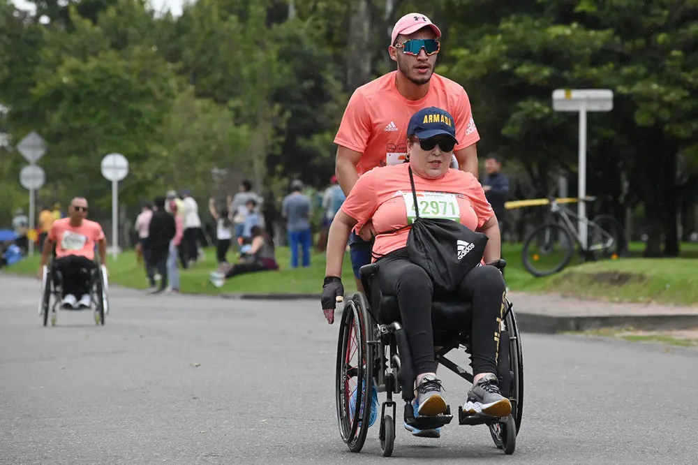 Mujer discapacitada en silla de ruedas corriendo la media maratón de bogotá 2023