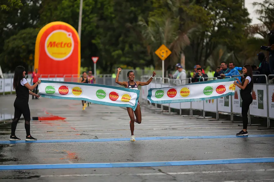 Mujer cruzando meta en la carrera de la media maratón de Bogotá