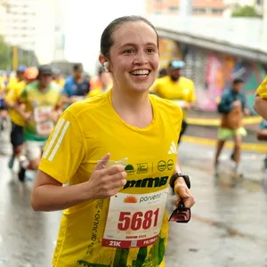 Mujer sonriente corriendo carreras de media distancia en el atletismo