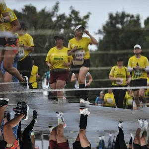 Reflejo de corredores en charco sobre el asfalto