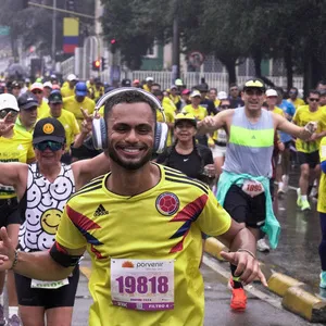 Hombre feliz corriendo la media maratón de Bogotá con la camisa de Colombia en el recorrido