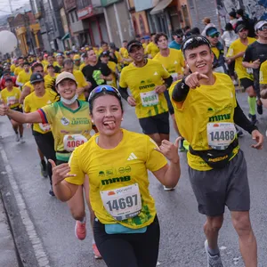 Participantes corriendo por una calle icónica de Bogotá en la Media Maratón