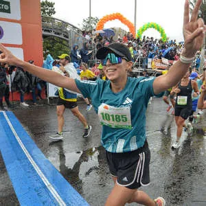 Corredora sonriente cruzando la línea de meta en la media maratón de Bogotá