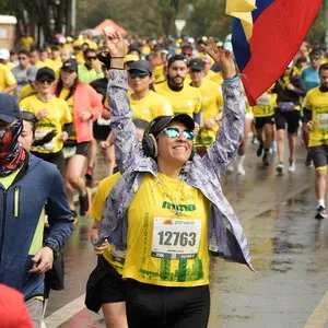 Mujer corriendo media maraton mientras ve la bandera de colombia