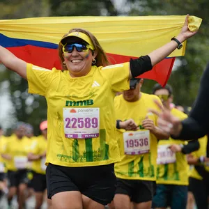 Mujer corriendo con alegría en la media maratón de Bogotá.