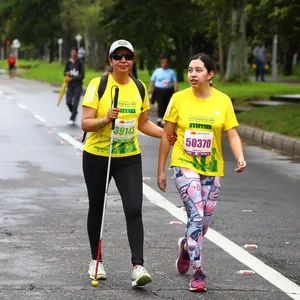 Participante con discapacidad visual corriendo con su guía en la carrera hoy Bogotá