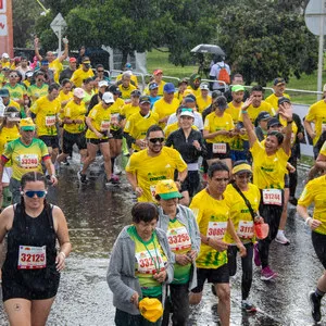 Gran número de corredores cruzando el arco de salida bajo la lluvia