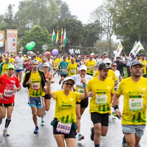 Mujer corriendo con ambas manos arriba mientras sonríe