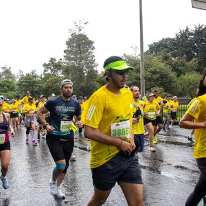 Hombre con visera verde, corriendo bajo la lluvia