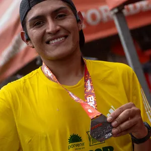 Joven sonríe mientras enseña medalla