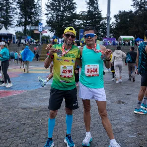 Dos hombres enseñando medalla de 21K mientras posan para fotos