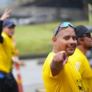 Hombre con gafas levanta la mano y señala a cámara