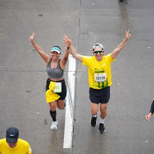 Hombre y mujer corren tomados de la mano levantando la mano