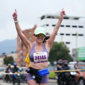 Mujer con ropa color morado levanta las manos al cielo y celebra estar próxima a llegar