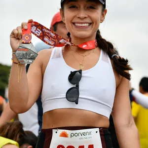 Mujer con gorra negra muestra medalla de 21 K