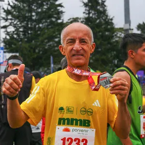 Hombre mayor con mano arriba y enseñando su medalla