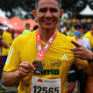 Hombre señalando a cámara y mostrando medalla de la media maratón de Bogotá