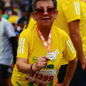 Atleta mujer inclinada al frente mostrando su medalla de 10 K